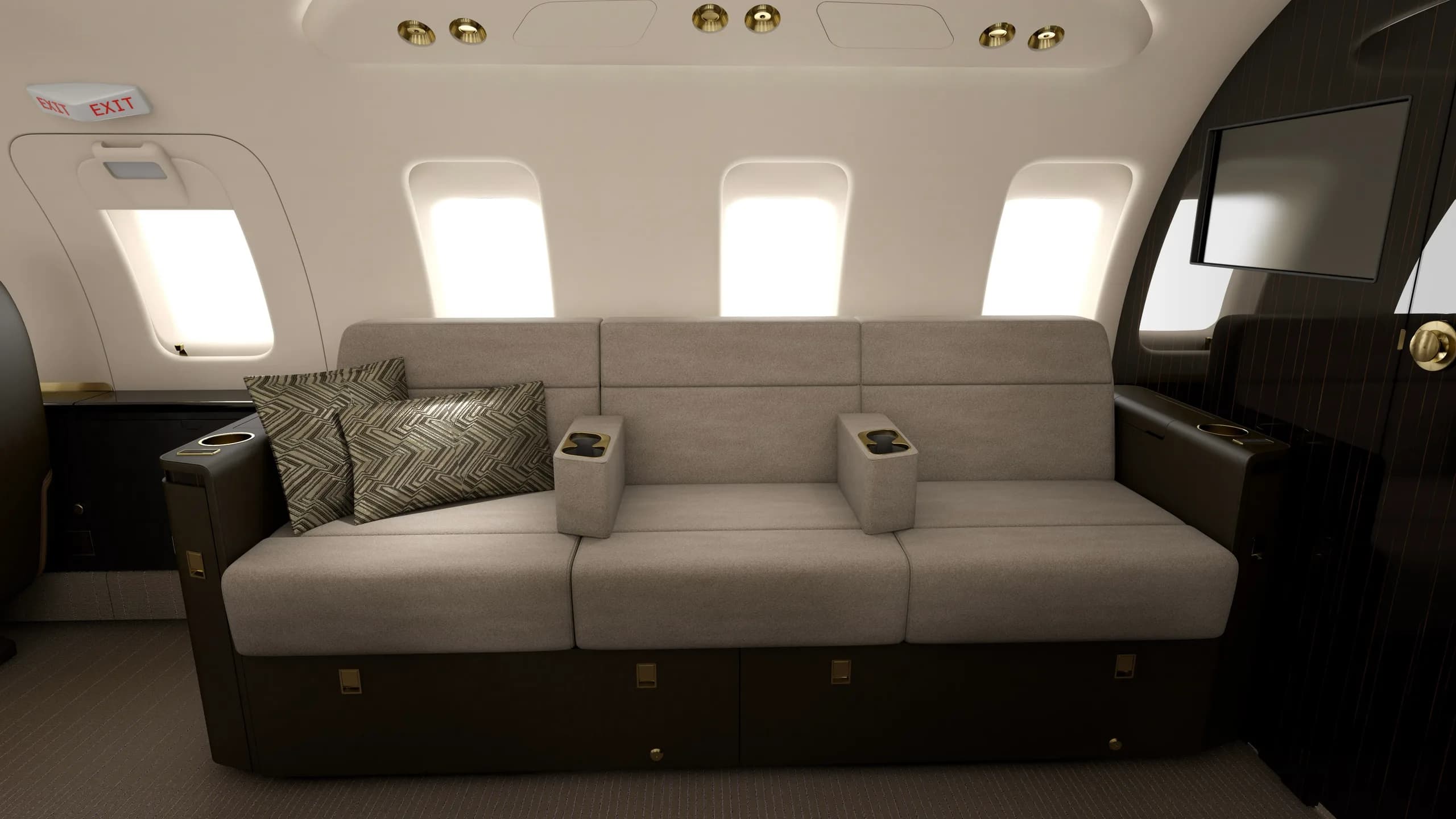 A grey three-seat sofa with patterned pillows inside a luxurious aircraft cabin.