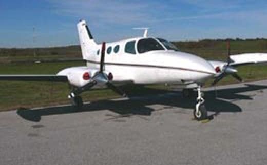 A small white twin-engine aircraft sits on the tarmac.