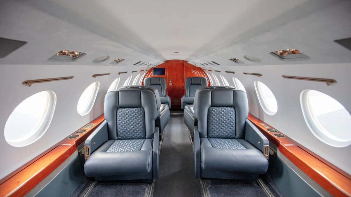 The interior of a Falcon jet with leather seats.
