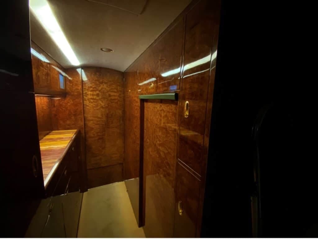 A view of the aircraft's galley or entryway, featuring rich dark wood paneling and a counter space.