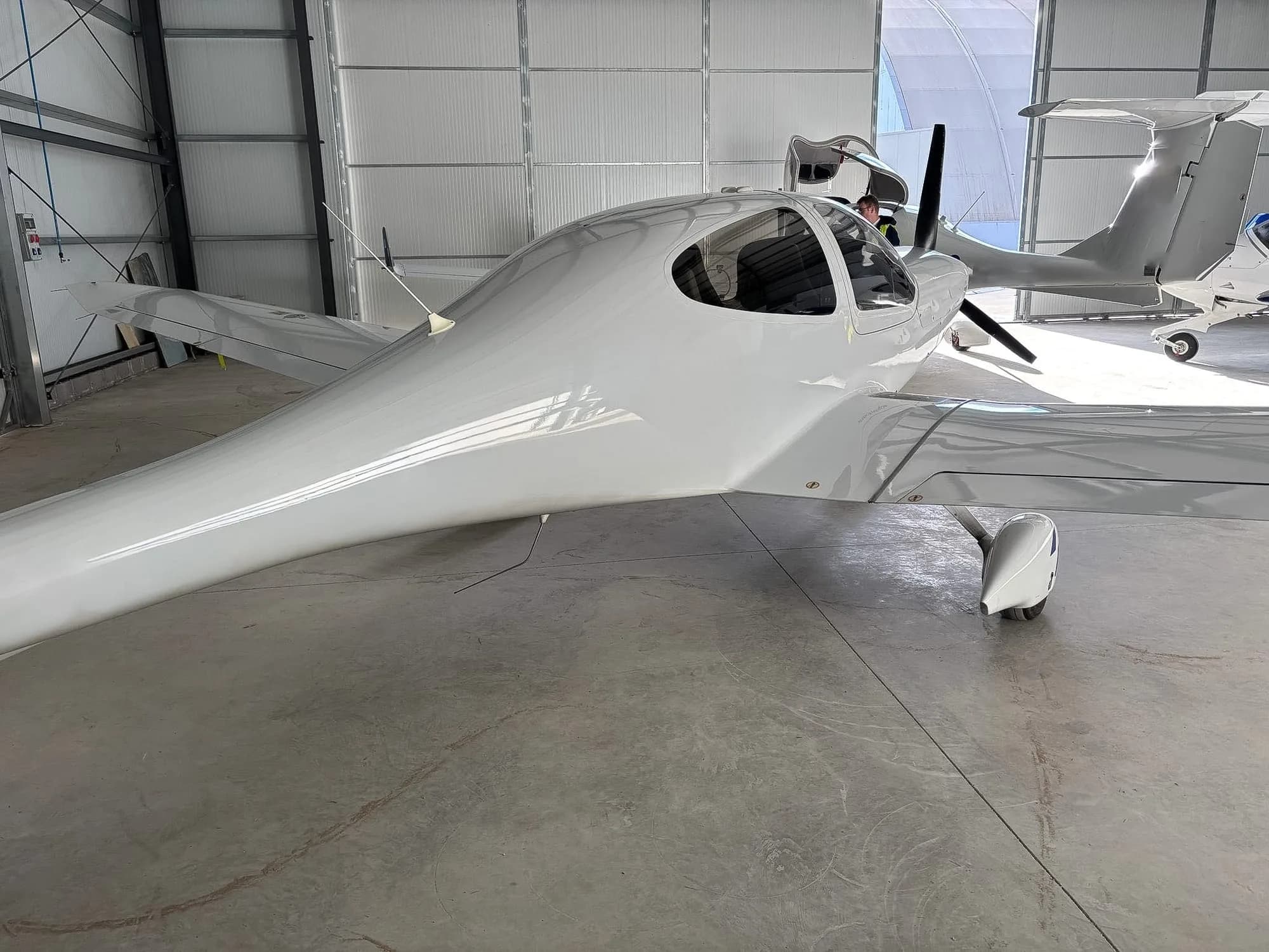 Side view of a white Diamond DA40 aircraft inside a hangar.
