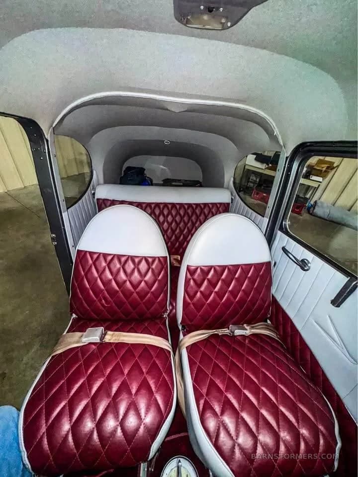 The rear cabin of an aircraft with two red and white quilted seats and seatbelts.