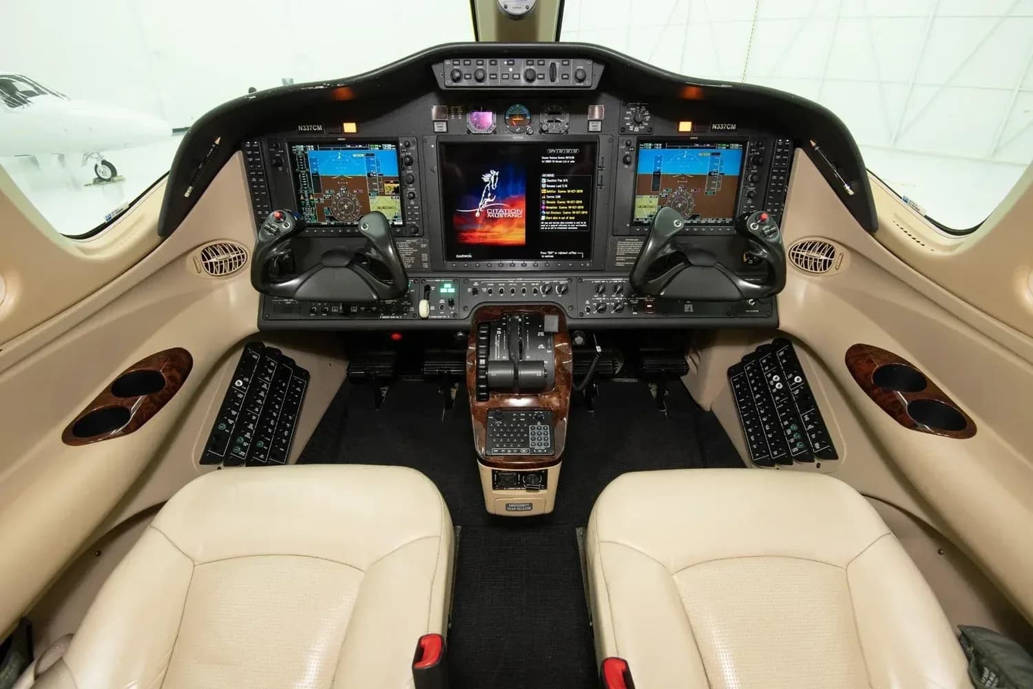 The cockpit of a Cessna Citation M2 with two beige pilot seats and a modern glass panel display.