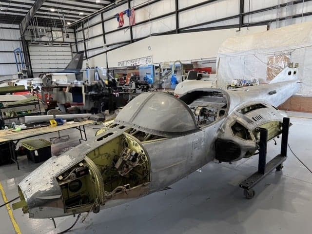 A partially disassembled aircraft in a hangar.