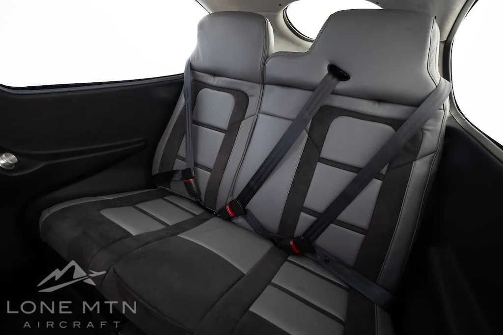 The gray and black rear passenger seats of a Cirrus SR22T aircraft, featuring integrated seatbelts.