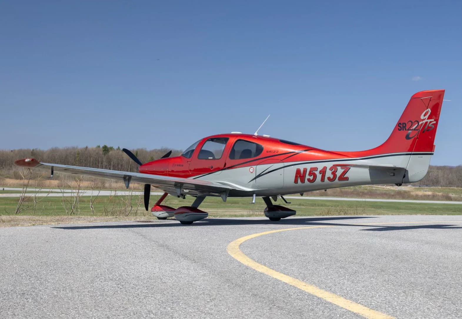 A red and grey Cirrus SR22T aircraft (N513Z) parked on an asphalt runway.