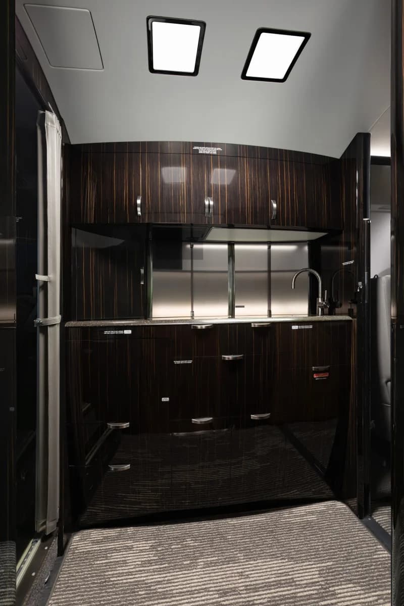 Galley area with dark wood cabinets and stainless steel backsplash.