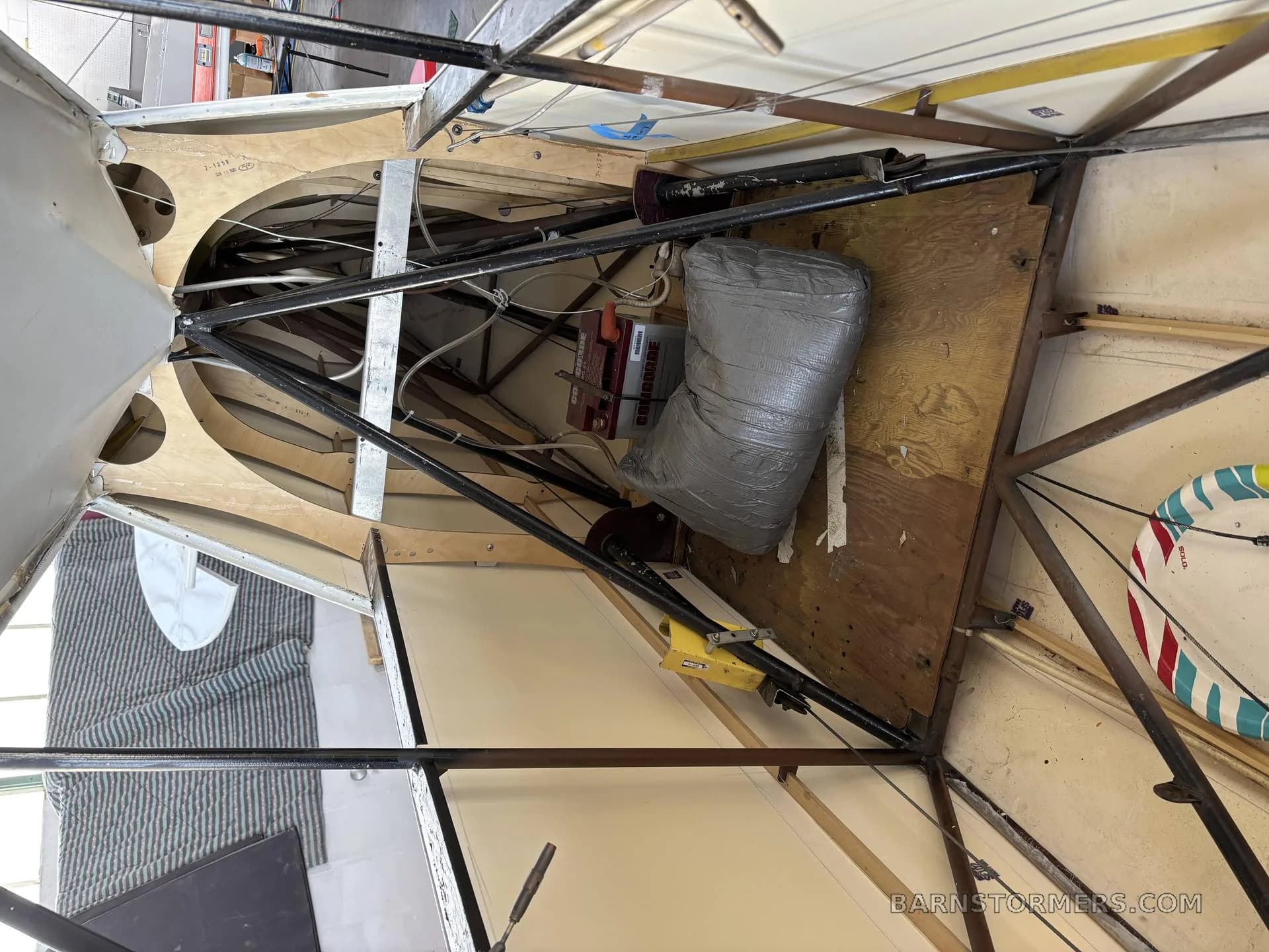 The exposed internal structure of a light aircraft fuselage, showing wooden ribs, metal tubing, and components.