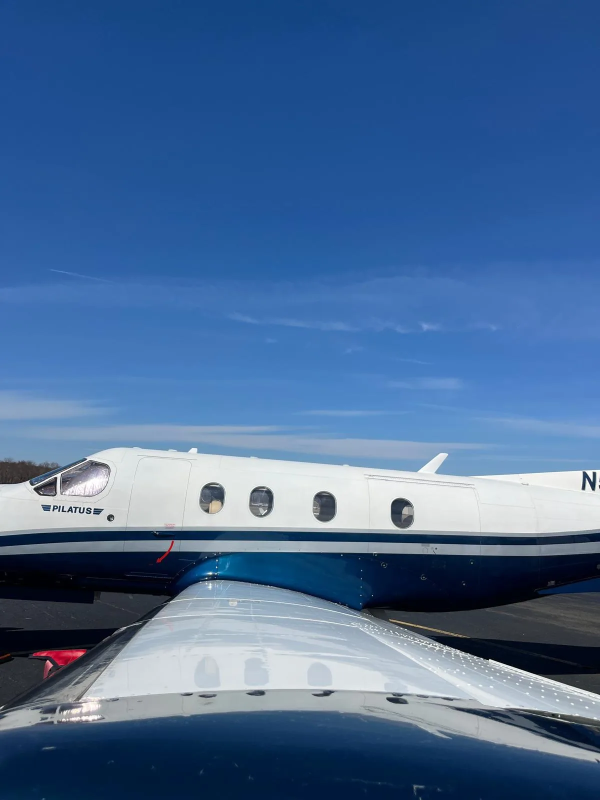A side view of the Pilatus PC-12 aircraft with white and blue livery, seen from over the wing.