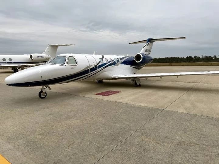 A white and blue Cessna Citation CJ4 business jet (N734MD) parked on an airport tarmac.
