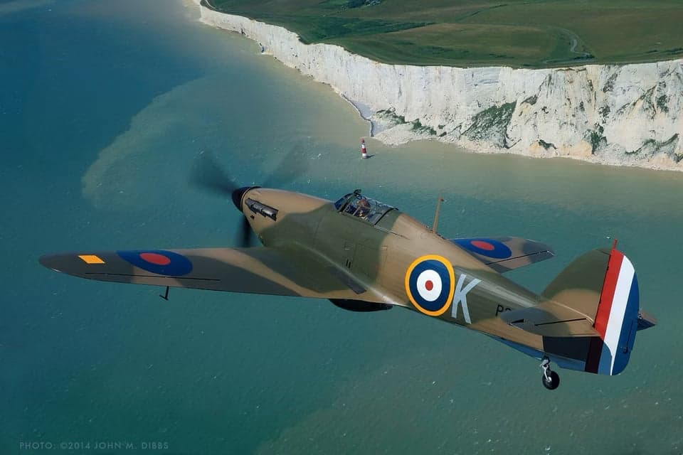 Hawker Hurricane fighter in flight, side view against clouds.