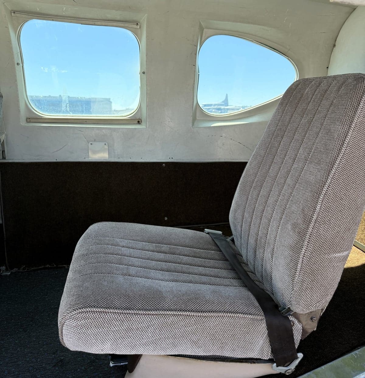 A single seat inside the aircraft cabin with a view out the window.