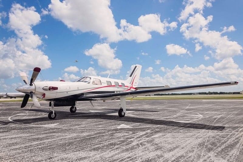 Piper Meridian aircraft parked on the tarmac under a partly cloudy sky.