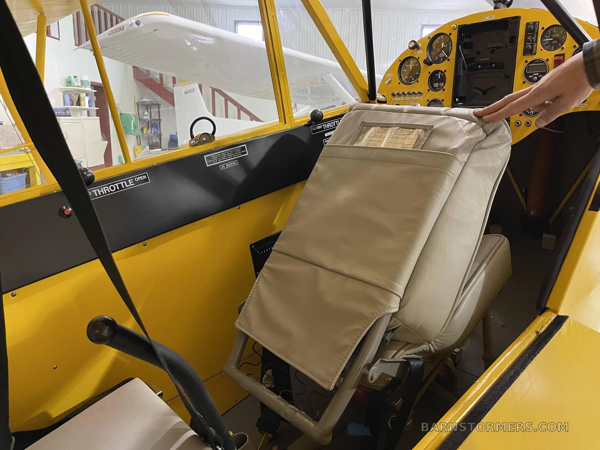 The interior of a yellow aircraft showing beige seats and part of the instrument panel.