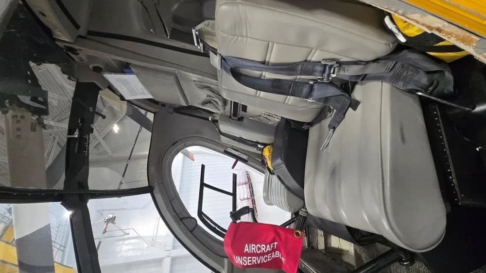 An interior view of the helicopter cabin, showing grey seats and a red "AIRCRAFT UNSERVICEABLE" flag.