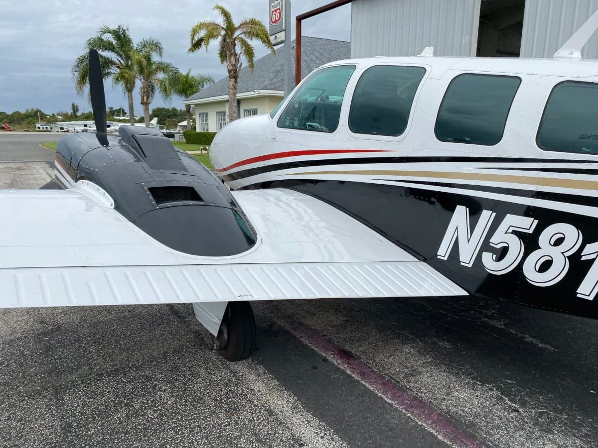 A close-up side view of the fuselage and wing of a white and black twin-engine aircraft with registration N581PS.