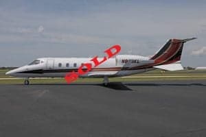 A Learjet aircraft with registration N813KL is parked on the tarmac, marked with a 'SOLD' overlay.