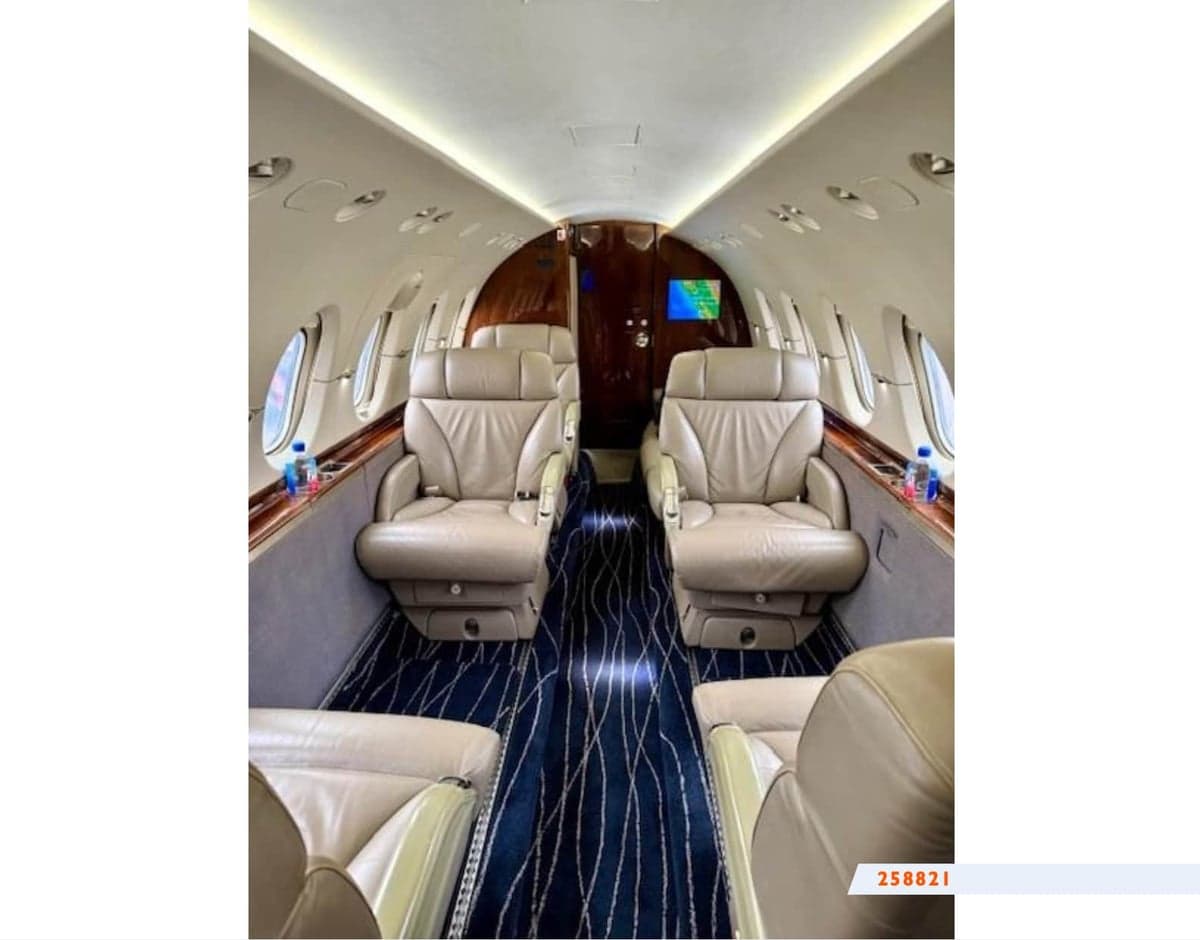 Aircraft cabin with leather seats and blue carpet.