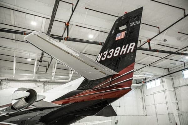The tail of a Citation jet, N338HR, is visible in a hangar.