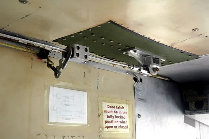 A close-up of an aircraft door latch mechanism with a diagram and safety instructions.
