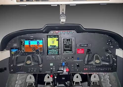 A modern aircraft cockpit featuring multiple digital displays and dual yokes.