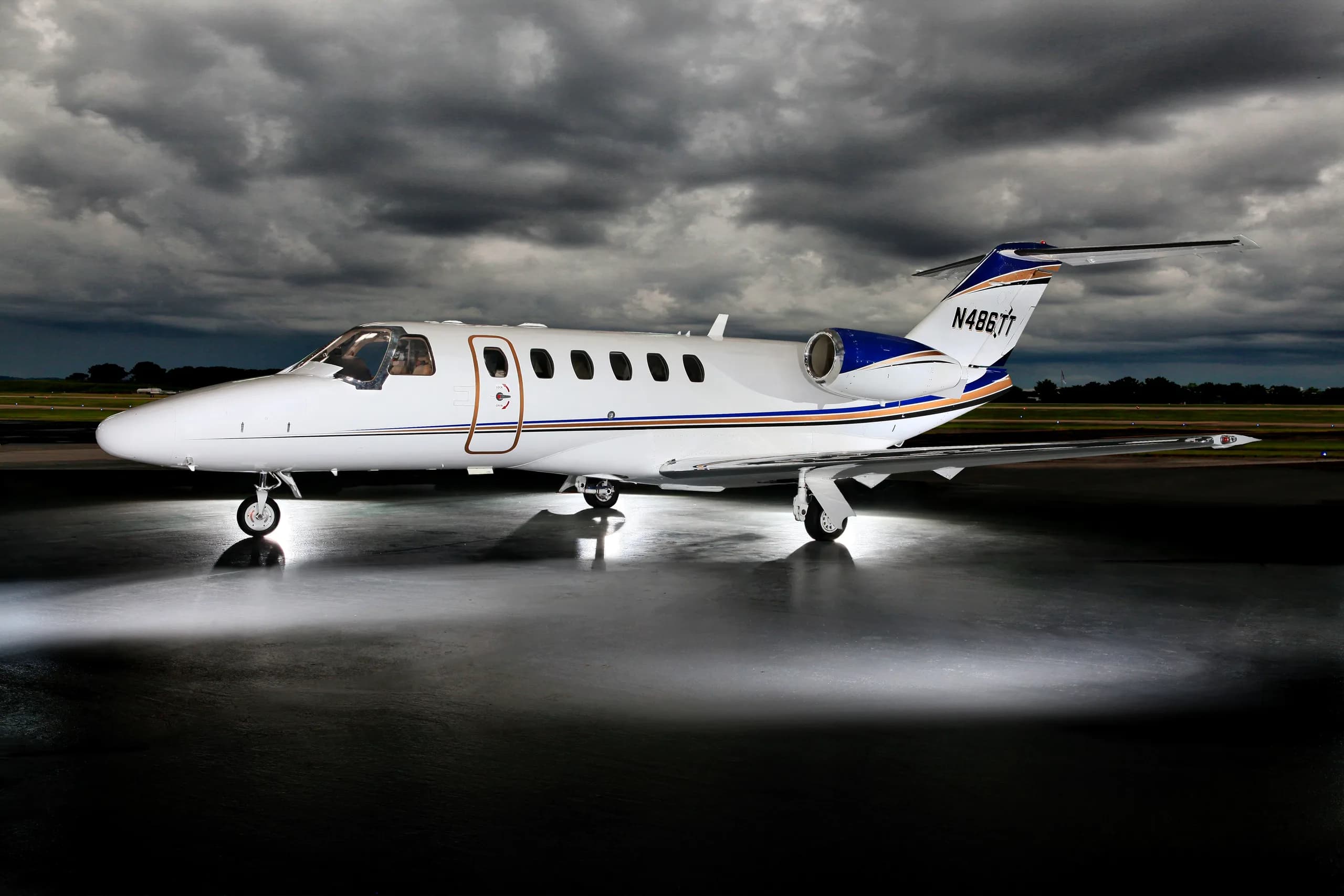 A Cessna Citation CJ3+ aircraft with registration N486TL is parked on the tarmac under a dramatic sky.