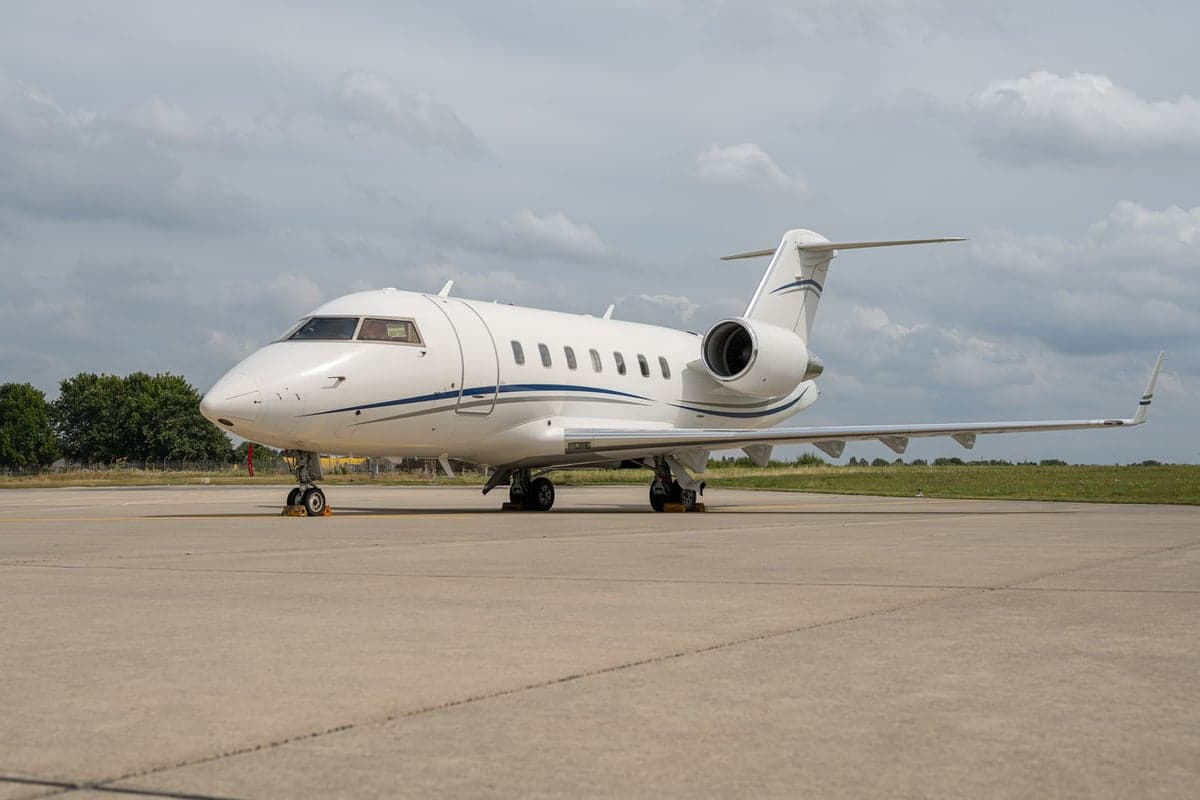Side view of a white jet with blue accents parked on the tarmac.