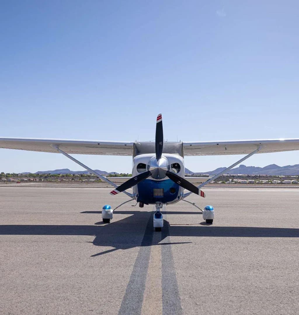 A head-on view of a white and blue Cessna Stationair N515AD parked on an airfield.