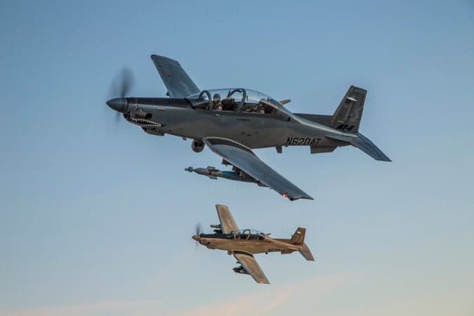 Two AT-6 light attack aircraft in flight against a clear sky.