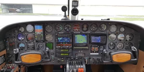 The tan leather interior cabin of a private aircraft, looking forward towards the cockpit.