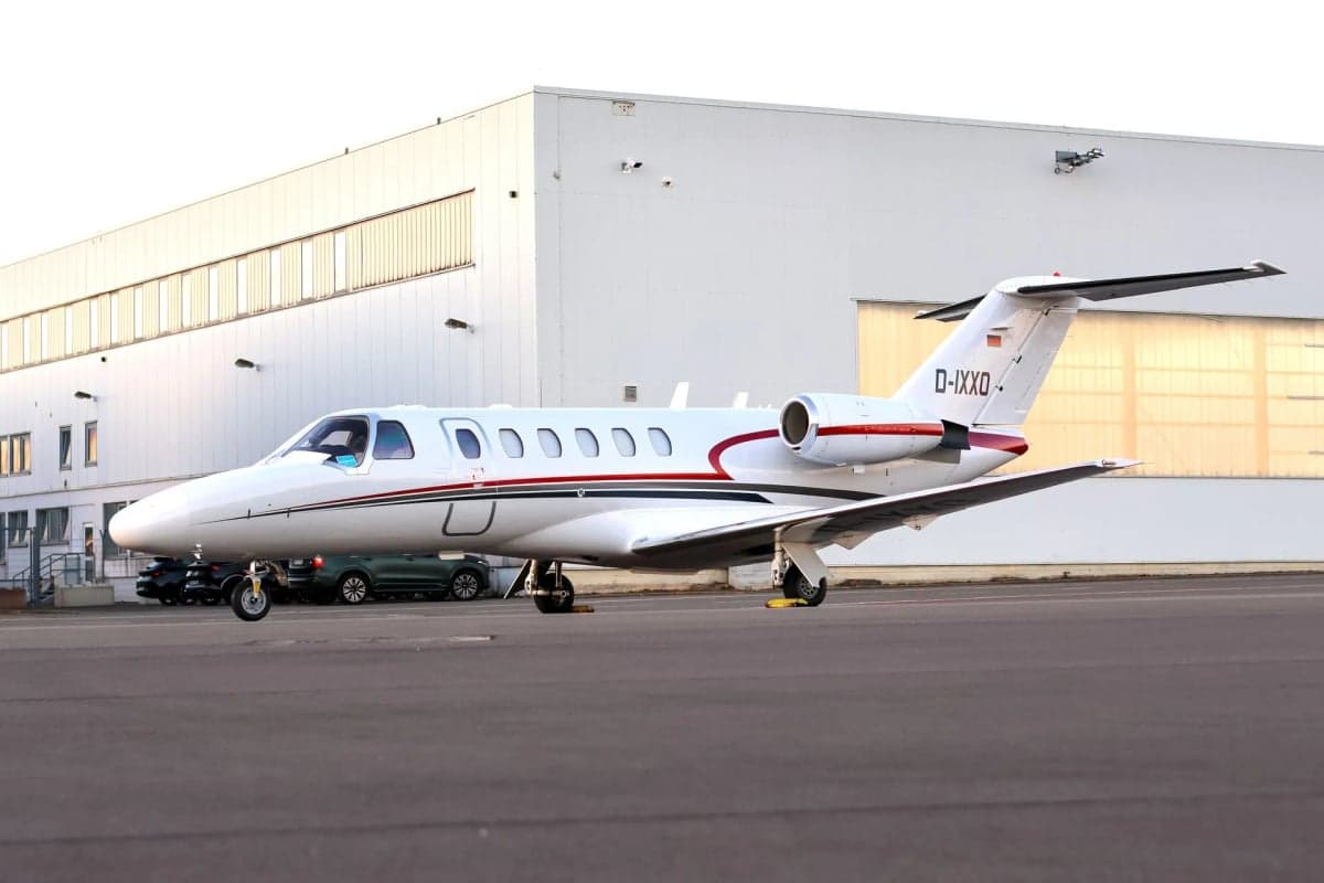 Cessna Citation CJ1+ aircraft with registration D-IXXO parked in front of a building.