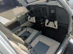 The cockpit of a Beechcraft Bonanza with white seats and a modern instrument panel.