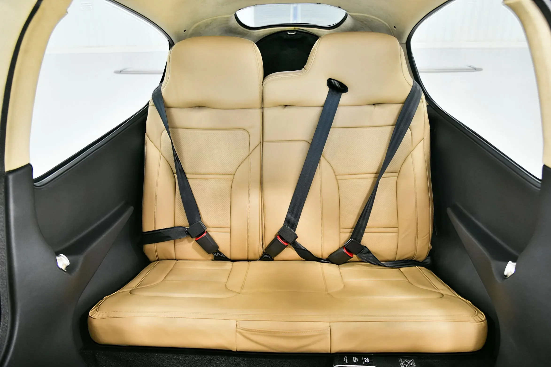 The tan leather rear seats of a Cirrus SR22 aircraft cabin, viewed from the front.