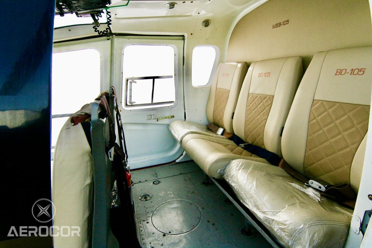 The beige passenger cabin seats of a helicopter, with 'BO-105' embroidered on them.