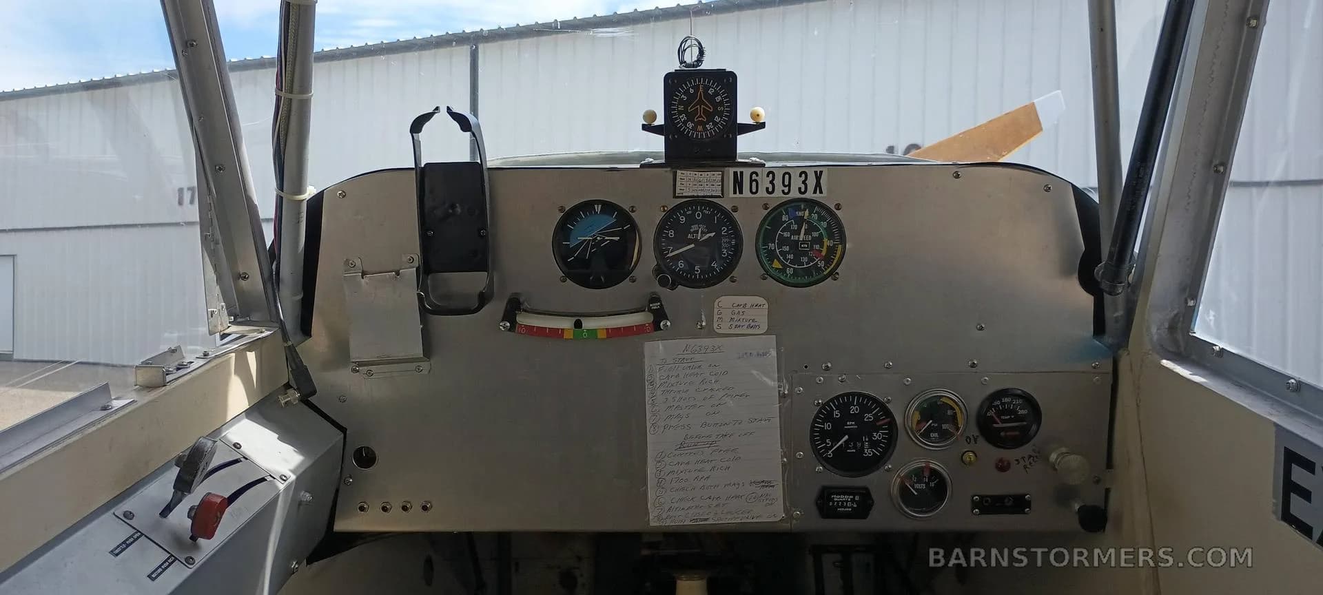 The instrument panel of a small aircraft, N6393X, with various gauges, a compass, and a checklist.