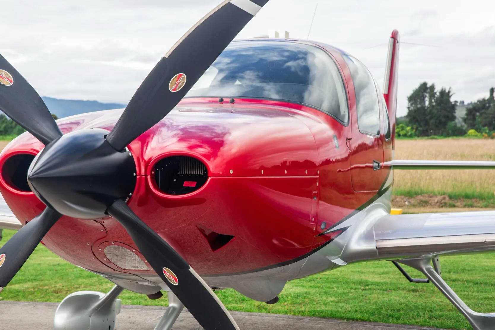 Close-up of the front-right side of the red and silver Cirrus SR22T aircraft, showing the propeller.