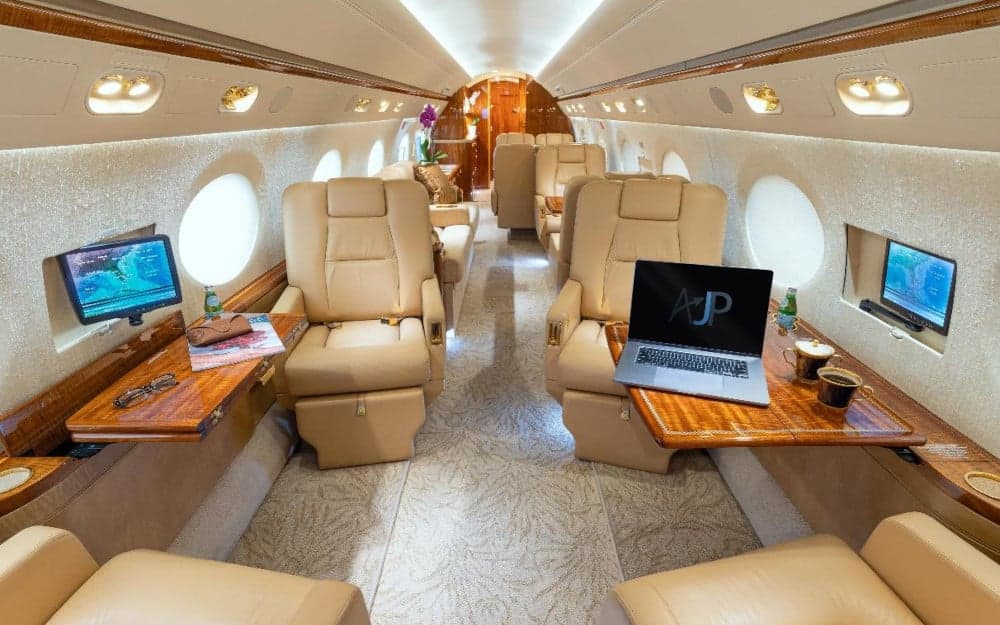 The interior of a private jet with leather seats and wood accents.