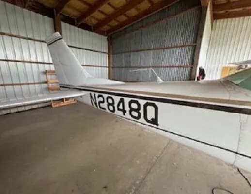 The tail section of a white and gold Cessna aircraft, N2848Q, is visible inside a hangar.