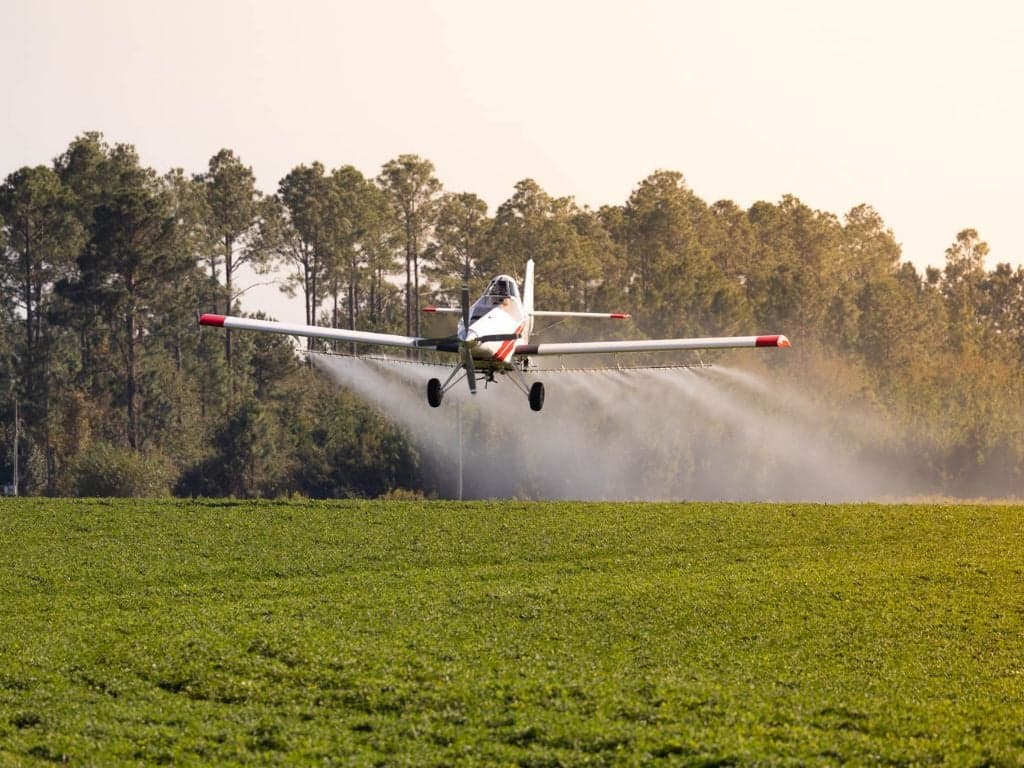 Crop duster aircraft spraying a field.