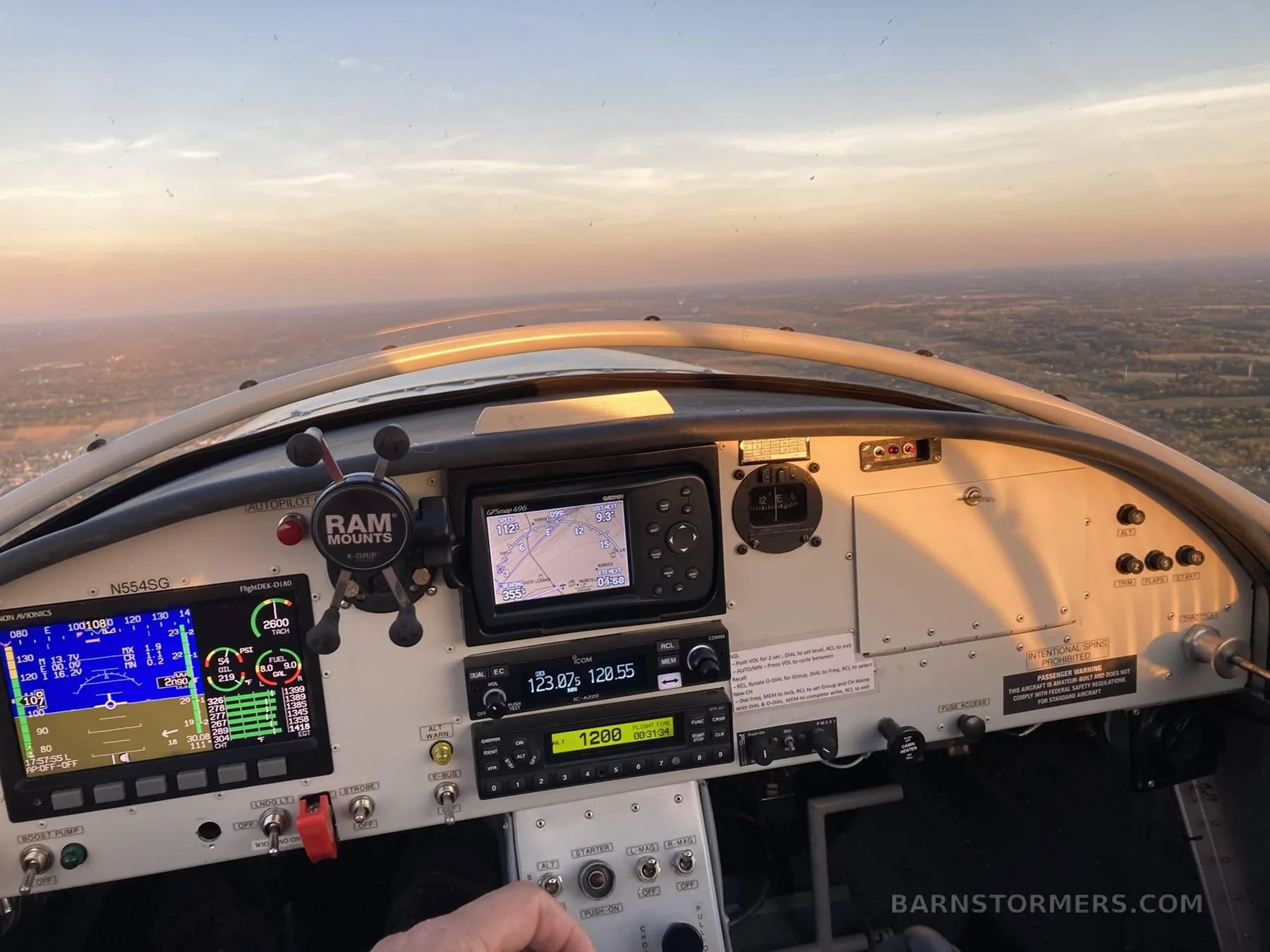 The cockpit of an aircraft with a modern glass panel display, GPS, and radio, showing a sunset view outside.