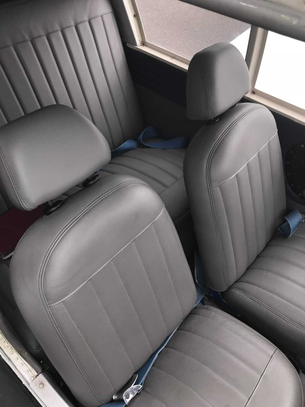 View of the gray leather passenger seats in the interior of a light aircraft.