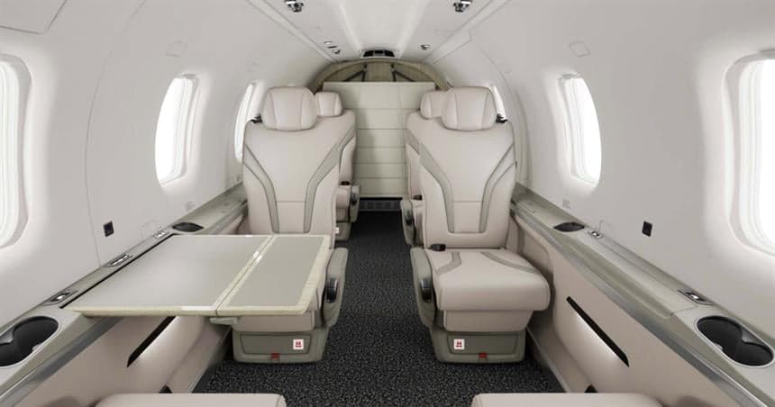 A view of the interior cabin of a Pilatus PC-12 aircraft, showing the seating arrangement and table.