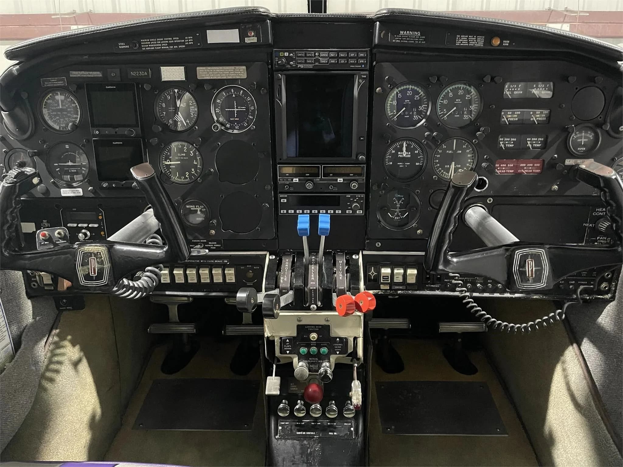 The cockpit of the Piper Aztec aircraft, showing the instrument panel, yokes, and central console.