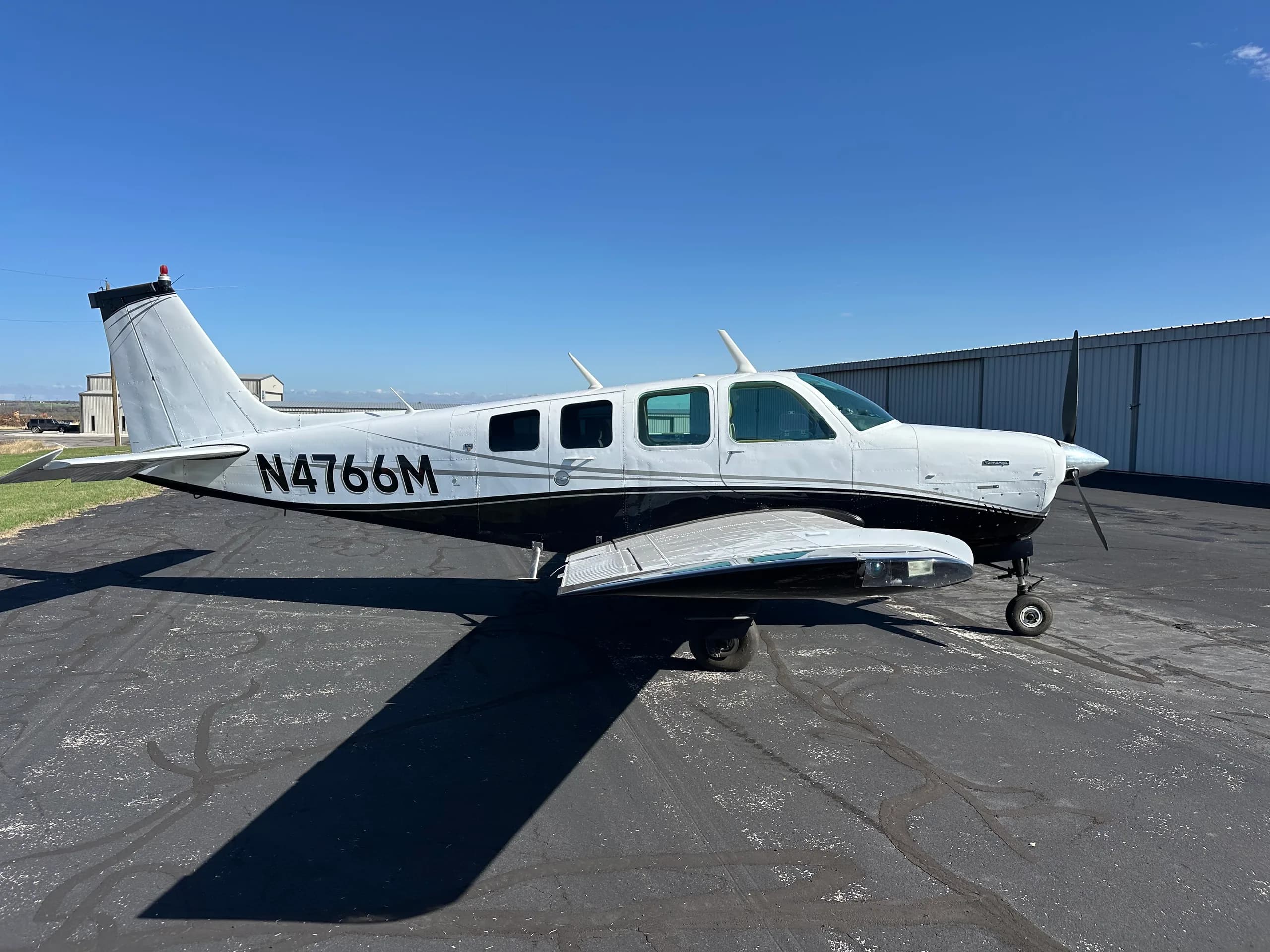 A Beechcraft Bonanza aircraft with registration N4766M is parked on the tarmac.