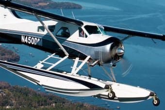 A white and blue float plane parked on a lake near the shore.