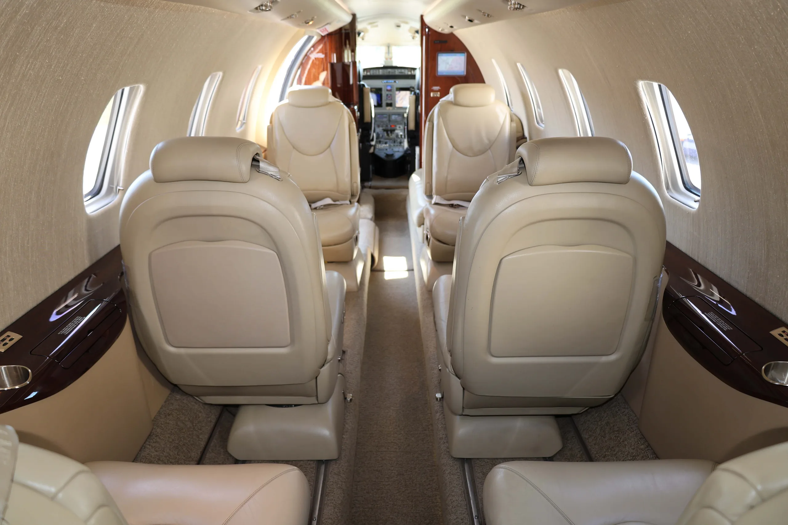 The aircraft cabin interior with light tan leather seats looking towards the cockpit.