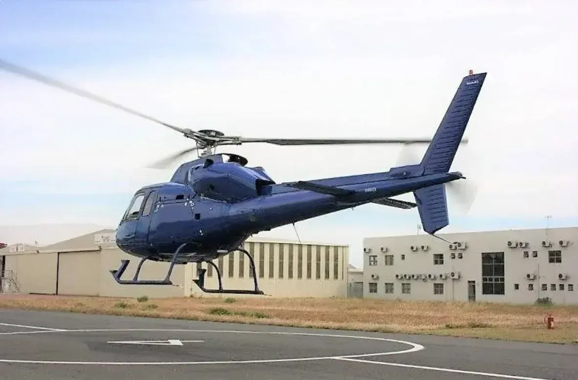 A blue helicopter taking off from a helipad.