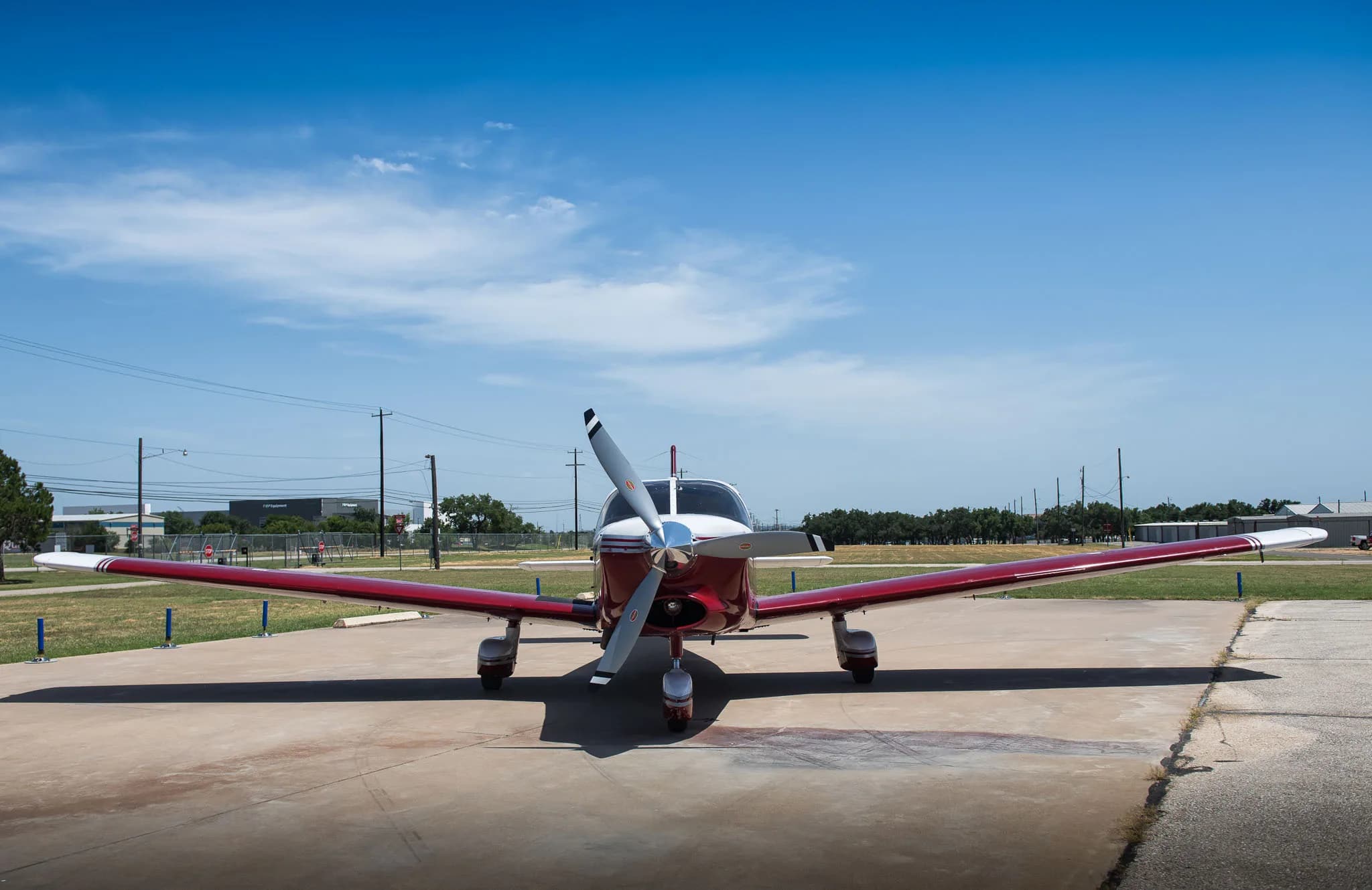 A head-on view of the red and white single-engine aircraft parked on the tarmac.