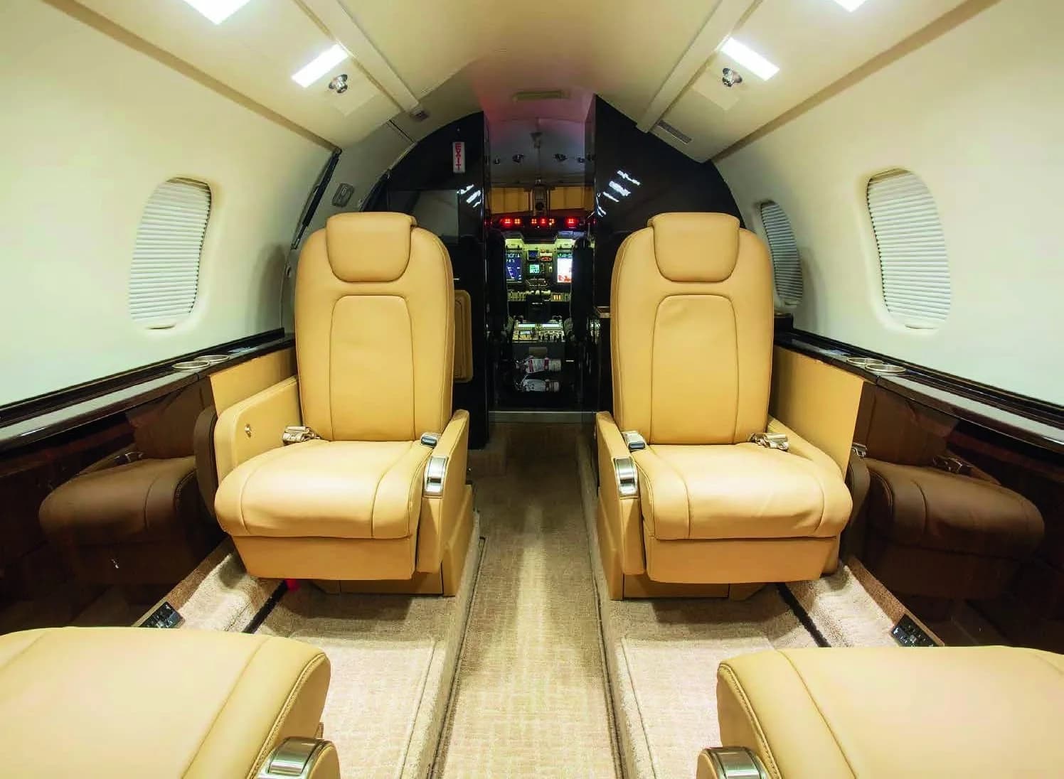 The forward cabin interior of a Learjet 75, featuring two tan leather seats facing forward.