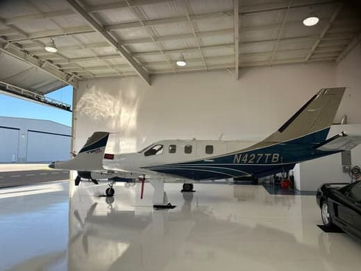 A TBM 930 aircraft is parked inside a hangar, showcasing its white and blue paint scheme.